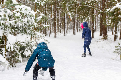 The boy sculpting a snowball with a girl. funny children in winter park playing snowballs, actively 