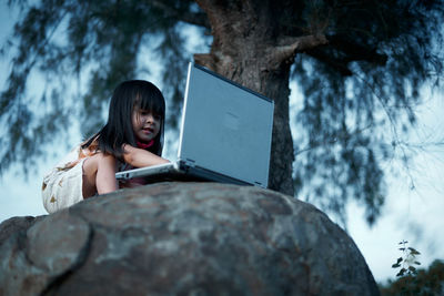 Woman sitting on tree trunk