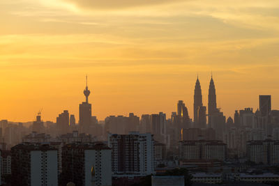 Modern cityscape against sky at sunset