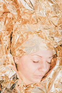 Close-up of woman with eyes closed wearing gold colored headwear