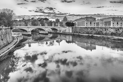 Bridge over river in city against sky