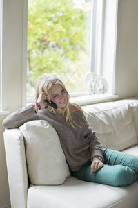 Teenage girl using mobile phone while relaxing on sofa at home