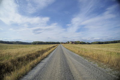 Road amidst field against sky