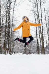 Full length of happy woman with arms outstretched on snow