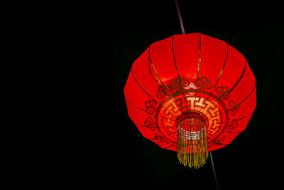 Low angle view of illuminated lantern against black background