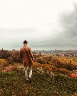 Rear view of shirtless man standing on field