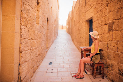 Woman sitting on table in alley