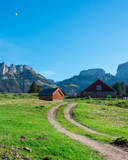 Houses on field by mountain against blue sky