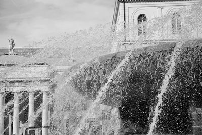 Water splashing on wall against sky