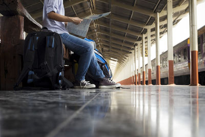 Low section of man sitting on bench at railroad station