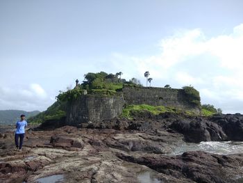 People standing on rock against sky