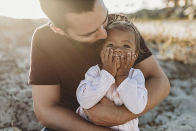 Close up of father holding young toddler girl at beach