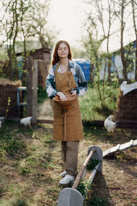 Smiling woman feeding chickens in farm