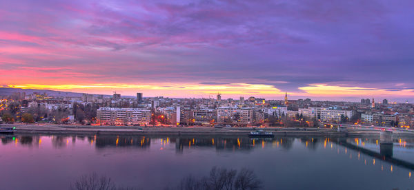 Illuminated cityscape against sky during sunset