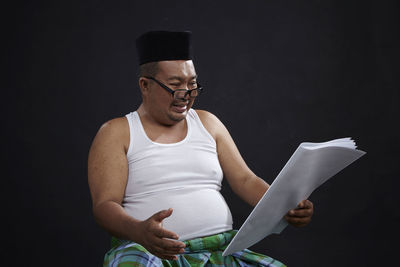 Midsection of man sitting against black background