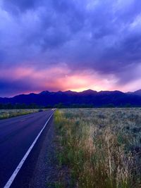 Empty road along countryside landscape at sunset