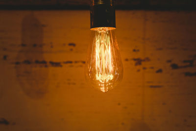 Illuminated light bulb hanging on wall