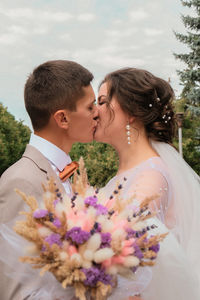 Groom hug and kiss bride in palm grove. wedding day for two. lovely weeding couple. young lovers. 