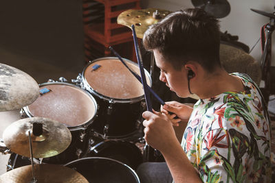 Teenager boy drummer playing on rehearsal in a studio. rock musician male teen performing a song. 