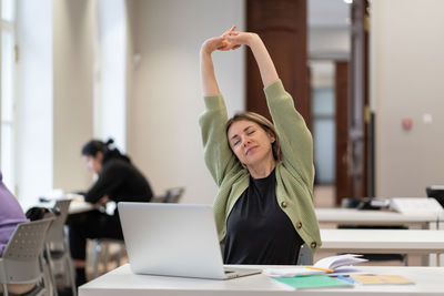 Middle-aged woman student warming up body and muscles at classroom, feeling satisfied with work done