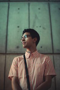 Portrait of young man standing against wall