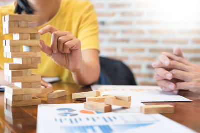 Business people playing with toy blocks at table in office