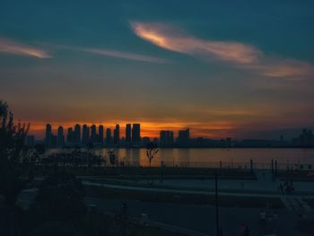 Silhouette buildings in city against sky during sunset