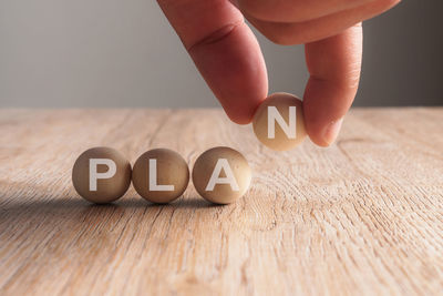 Cropped hand arranging balls with plan text on wooden table