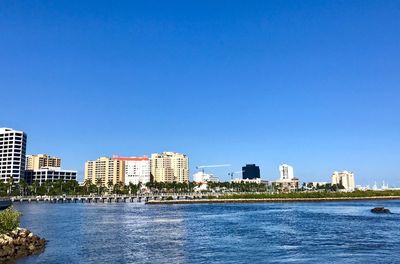 Sea by buildings against blue sky