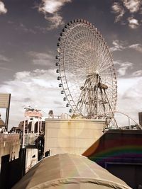 Low angle view of ferris wheel against cloudy sky