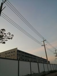 Low angle view of electricity pylon and building against sky
