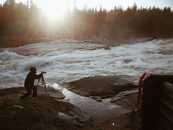 Man photographing on rock by river