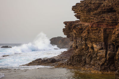 Scenic view of sea against clear sky with a breaking wave