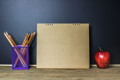 Close-up of diary with pencils and apple on table