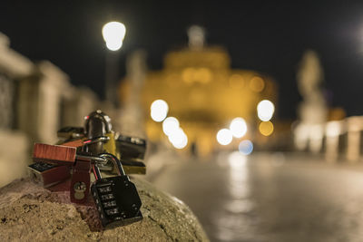 Close-up of padlocks on retaining wall at night