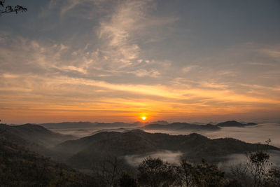 Scenic view of silhouette mountains against orange sky