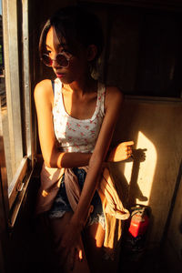 Young woman looking through window at home