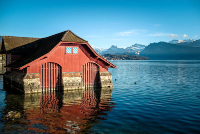 Stilt house by lake against sky