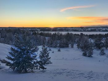 Scenic view of snow covered landscape against sky at sunset