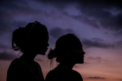 Silhouette friends against cloudy sky during sunset