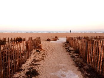 Wooden posts on beach against clear sky