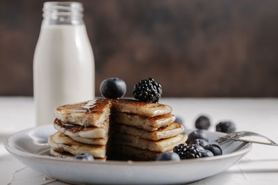 Still life of a stack of homemade pancakes with berries and syru