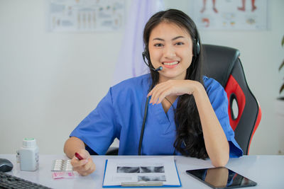 Portrait of a smiling young woman sitting on table