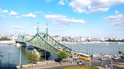 Bridge over river in city against sky