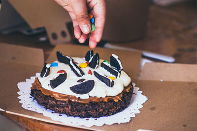 Cropped hand of person garnishing cake