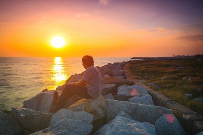 People sitting on beach against sky during sunset