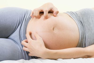 Midsection of pregnant woman lying on bed at home