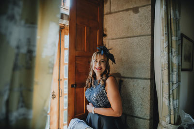 Portrait of smiling woman standing by door