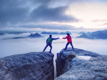 Rear view of people standing on rock against sky