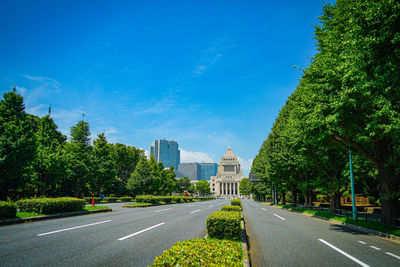 Road amidst trees against blue sky